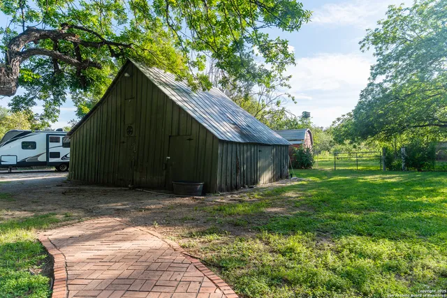 a backyard of a house with plants and large tree