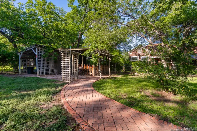 a view of a backyard with table and chairs and a large tree