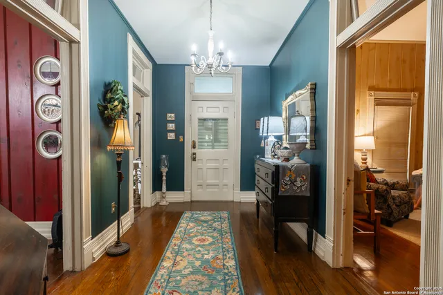 a view of a hallway with wooden floor and a chandelier