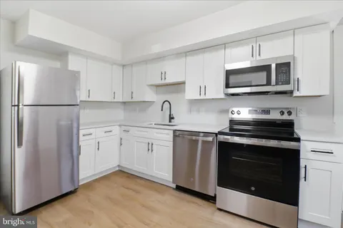 a kitchen with granite countertop a refrigerator stove and sink