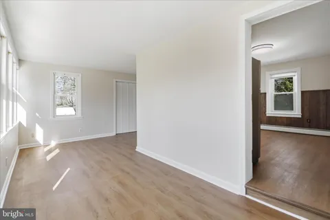 a view of an empty room with a window and wooden floor