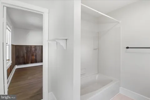 an empty room with wooden floor chandelier fan and windows