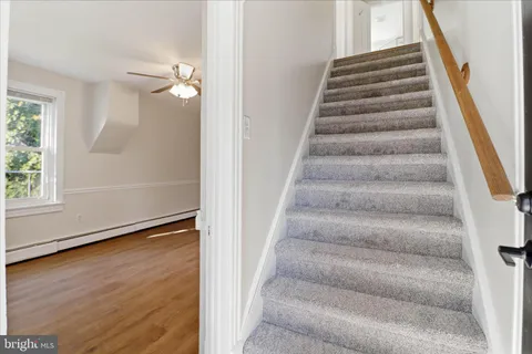 an empty room with wooden floor chandelier fan and windows