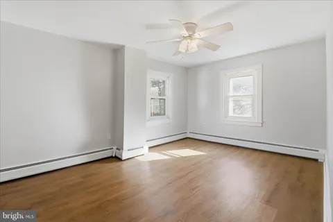a view of an empty room with window and chandelier fan