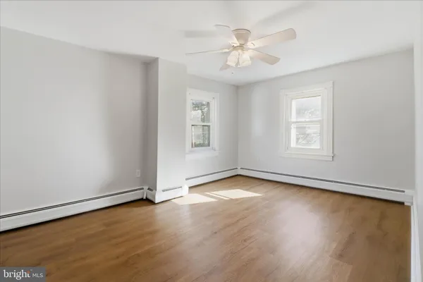 a view of an empty room with window and chandelier fan