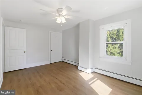 a view of an empty room with window and wooden floor