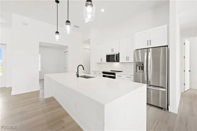 a kitchen with stainless steel appliances a refrigerator a sink a stove a microwave and island