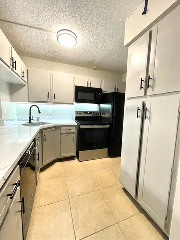 a kitchen with a sink a refrigerator and cabinets
