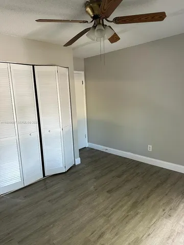 an empty room with wooden floor and fan