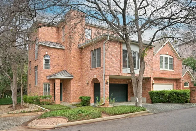 a front view of a brick house with a yard and plants