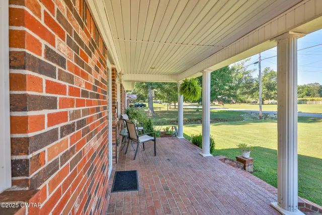 a porch with a table and chairs next to a yard