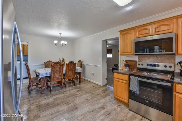 a kitchen with granite countertop stainless steel appliances a sink a refrigerator and cabinets