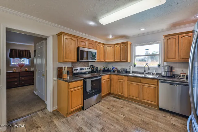 a kitchen with stainless steel appliances granite countertop a stove a sink dishwasher a refrigerator and cabinets with wooden floor