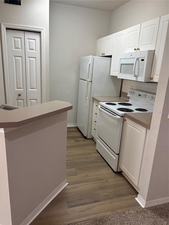 5180 Northridge Road, Unit 105 Sarasota, FL 34238 - Photo 2 of 12 a kitchen with white cabinets and white appliances