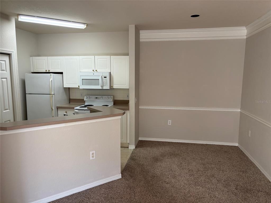 5180 Northridge Road, Unit 105 Sarasota, FL 34238 - Photo 4 of 12 a kitchen with a refrigerator a stove top oven and white cabinets
