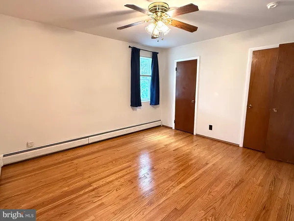 an empty room with wooden floor chandelier fan and windows