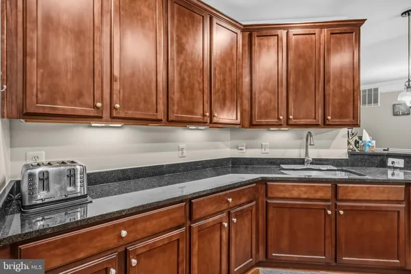 a kitchen with granite countertop stainless steel appliances wooden cabinets and a sink