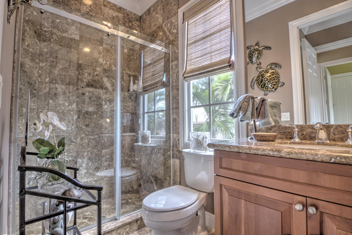 17106 Bay Street Jupiter, FL 33477 - Photo 23 of 52 a bathroom with a granite countertop sink a toilet a mirror and a shower