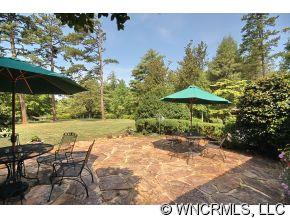 1184 Hunting Country Road Tryon, NC 28782 - Photo 2 of 12 a backyard of a house with table and chairs under an umbrella