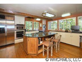 1184 Hunting Country Road Tryon, NC 28782 - Photo 6 of 12 a kitchen with stainless steel appliances granite countertop a stove top oven a sink with dining table and chairs