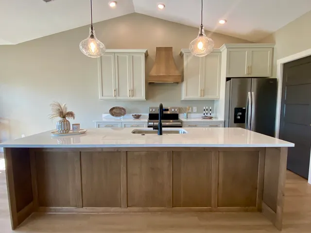 a large kitchen with stainless steel appliances a large counter top a sink a stove and a refrigerator