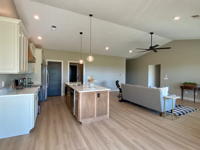 a kitchen that has a sink a microwave oven a stove and white cabinets with wooden floor