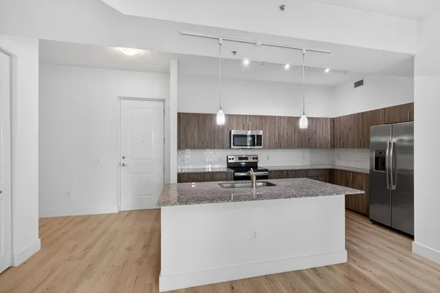 a kitchen with kitchen island granite countertop a sink cabinets and stainless steel appliances