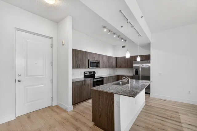 a kitchen with stainless steel appliances a sink stove refrigerator and cabinets