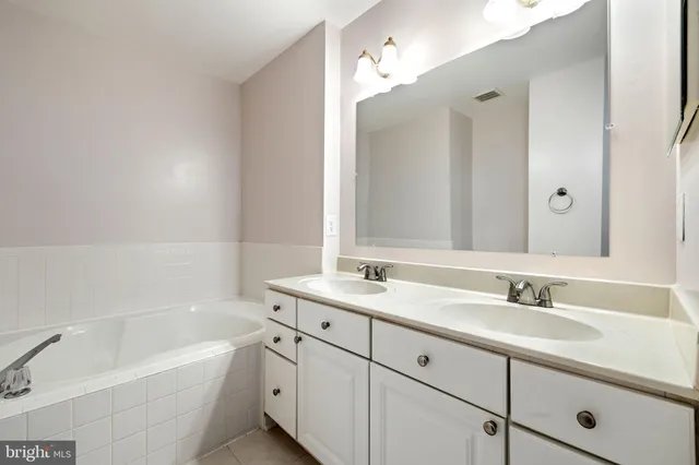 a bathroom with a tub sink double vanity granite and tub