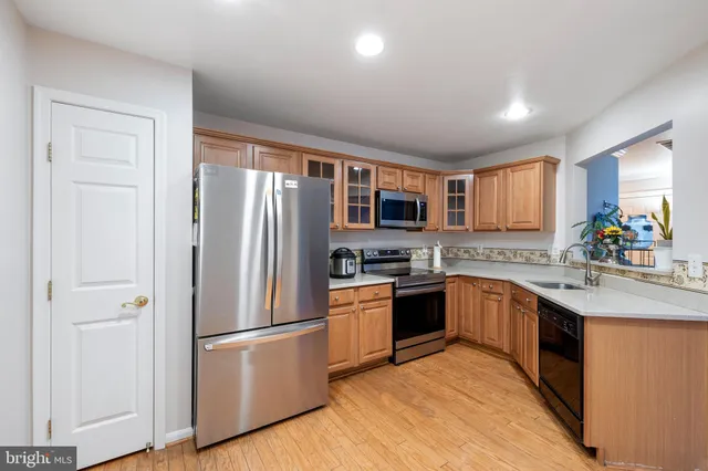 a kitchen with stainless steel appliances granite countertop refrigerator a sink dishwasher a stove top oven a refrigerator with island and chairs