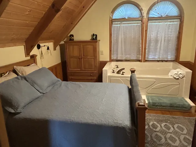 a bedroom with a bed and large windows
