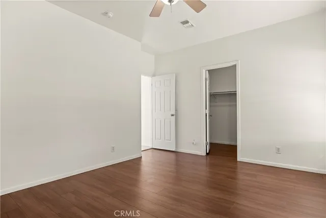 an empty room with wooden floor chandelier fan and windows