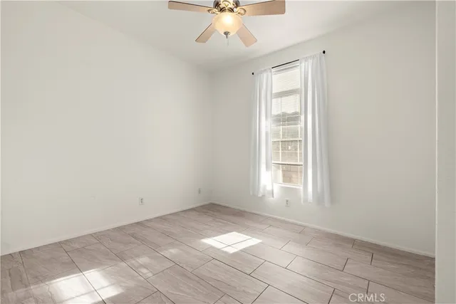 an empty room with chandelier fan and windows