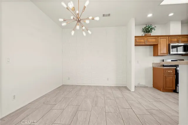 an empty room with a kitchen and a chandelier fan
