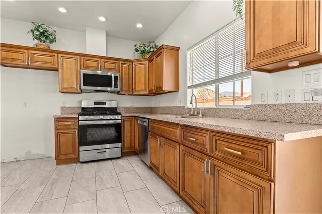 a kitchen with stainless steel appliances granite countertop a stove top oven a sink dishwasher and a microwave oven on the blue kitchen countertops