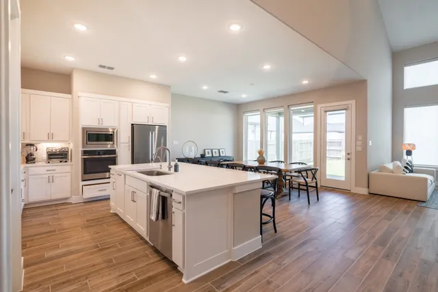 a large white kitchen with lots of counter top space and stainless steel appliances
