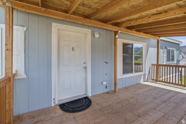 433 North 750 West Logan, UT 84321 - Photo 23 of 40 Covered wood-deck porch featuring a paneled entry door, light blue siding, and white-framed windows
