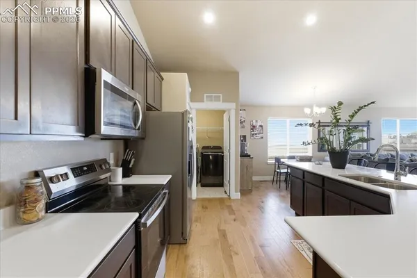 a kitchen with stainless steel appliances a sink a stove a refrigerator cabinets and a dining table