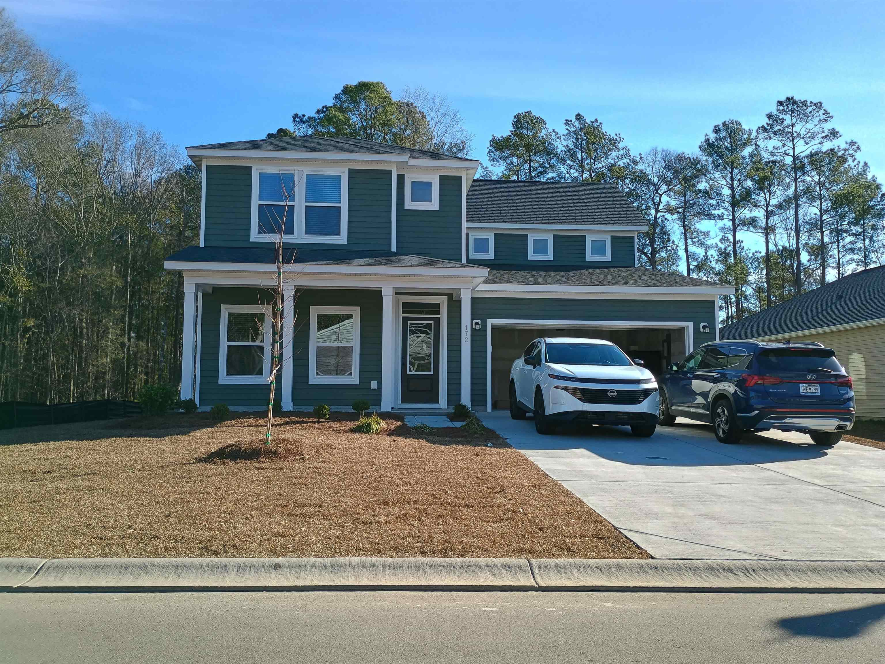 View of front of property with covered porch, driveway, and roof with shingles