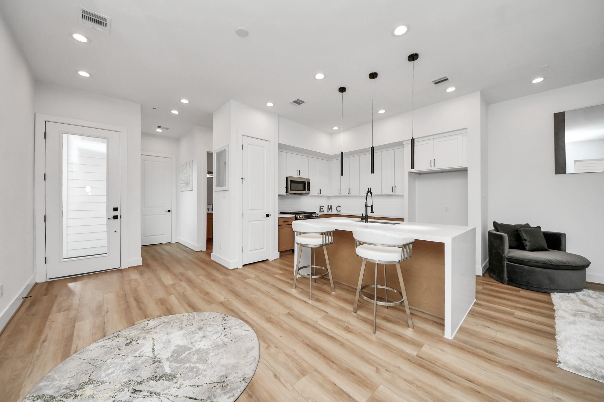 505 Middle Street Houston, TX 77003 - Photo 4 of 46 Discover the first floor's seamless blend of elegance and functionality, featuring an open-concept kitchen with sleek white cabinetry, modern lighting, and inviting wood floors that flow into a cozy living space perfect for entertaining or relaxing.
