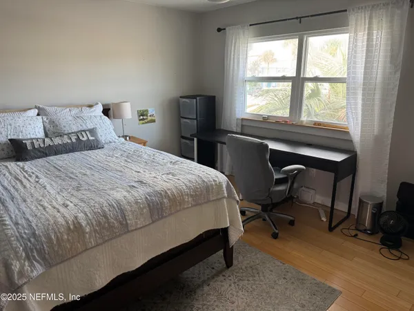 a bedroom with a bed a table and a large window