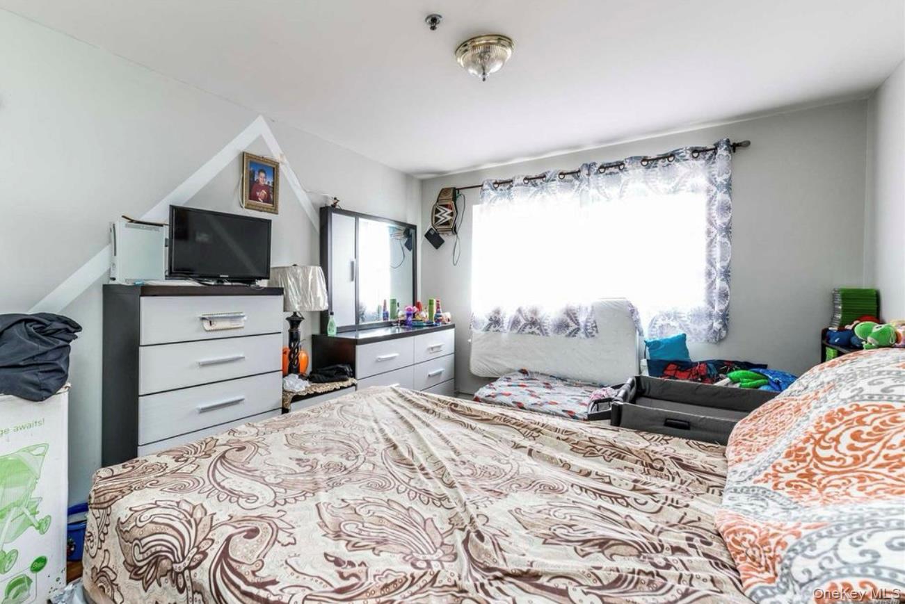 35-43 97th Street Queens, NY 11368 - Photo 8 of 10 a bedroom with a bed and a flat tv screen