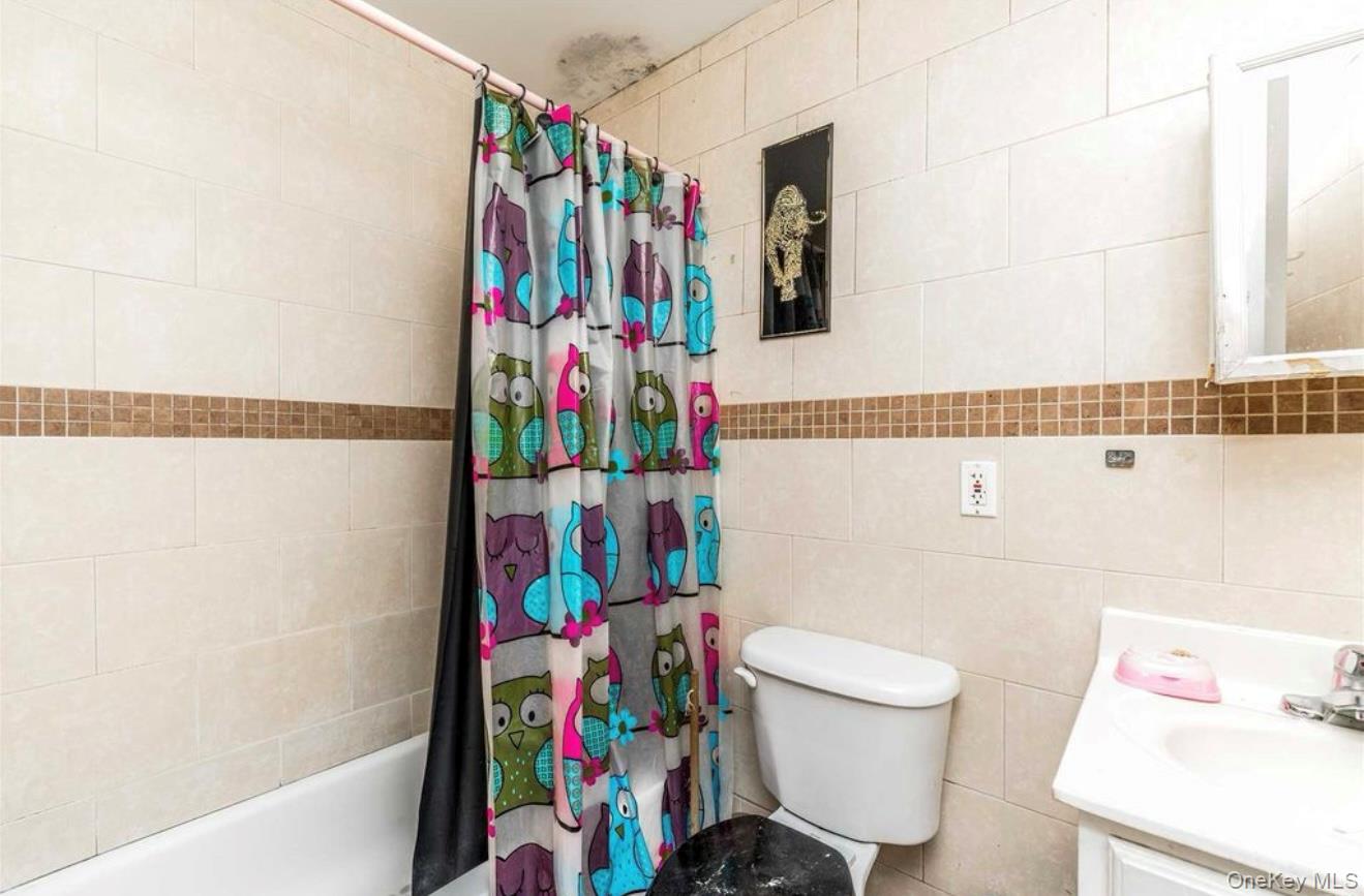 35-43 97th Street Queens, NY 11368 - Photo 9 of 10 a small bathroom with a sink a toilet and shower curtain