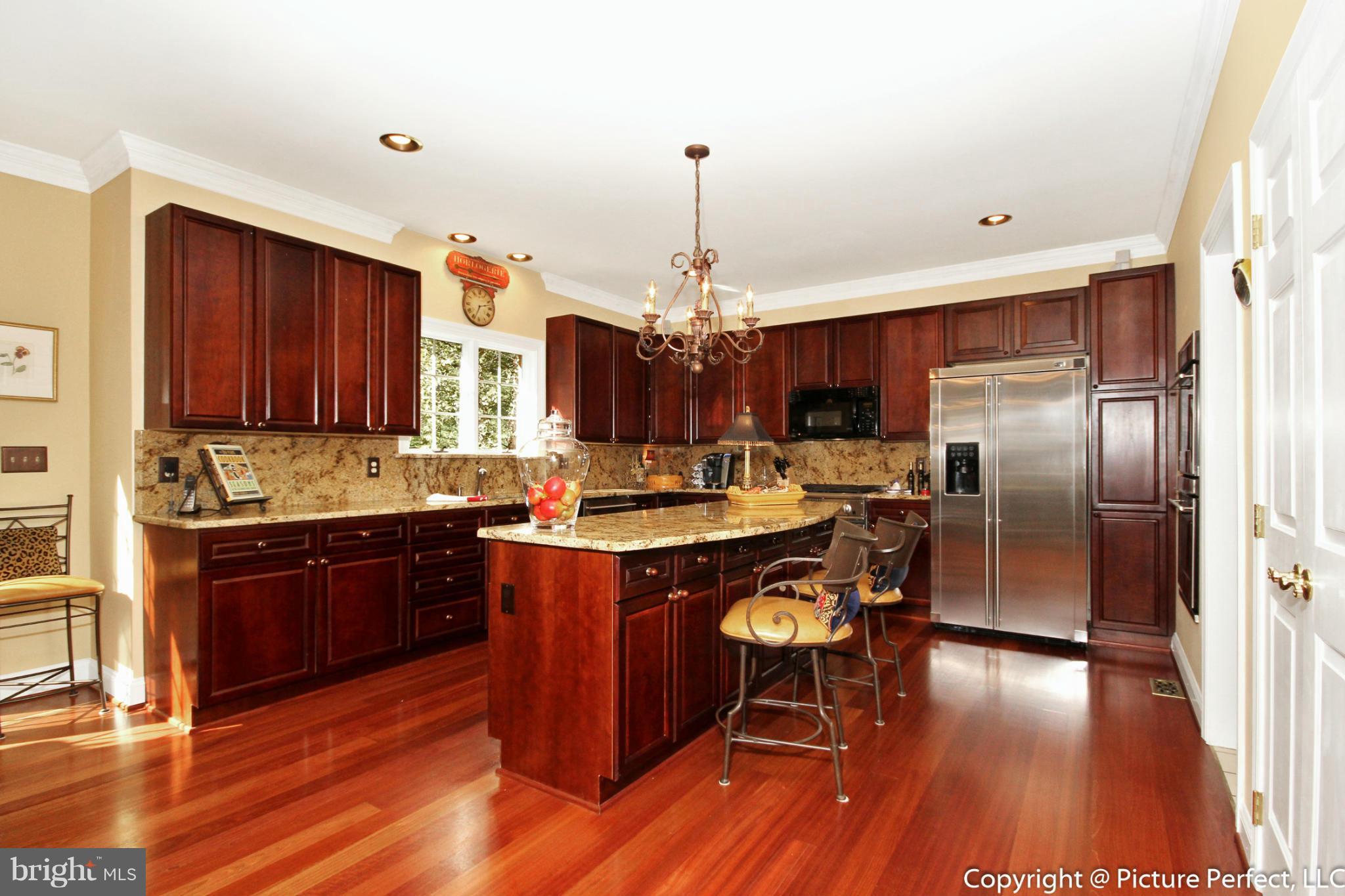 5380 Stone Road Frederick, MD 21703 - Photo 12 of 30 a kitchen with stainless steel appliances granite countertop a refrigerator a sink dishwasher a stove and a dining table with wooden floor