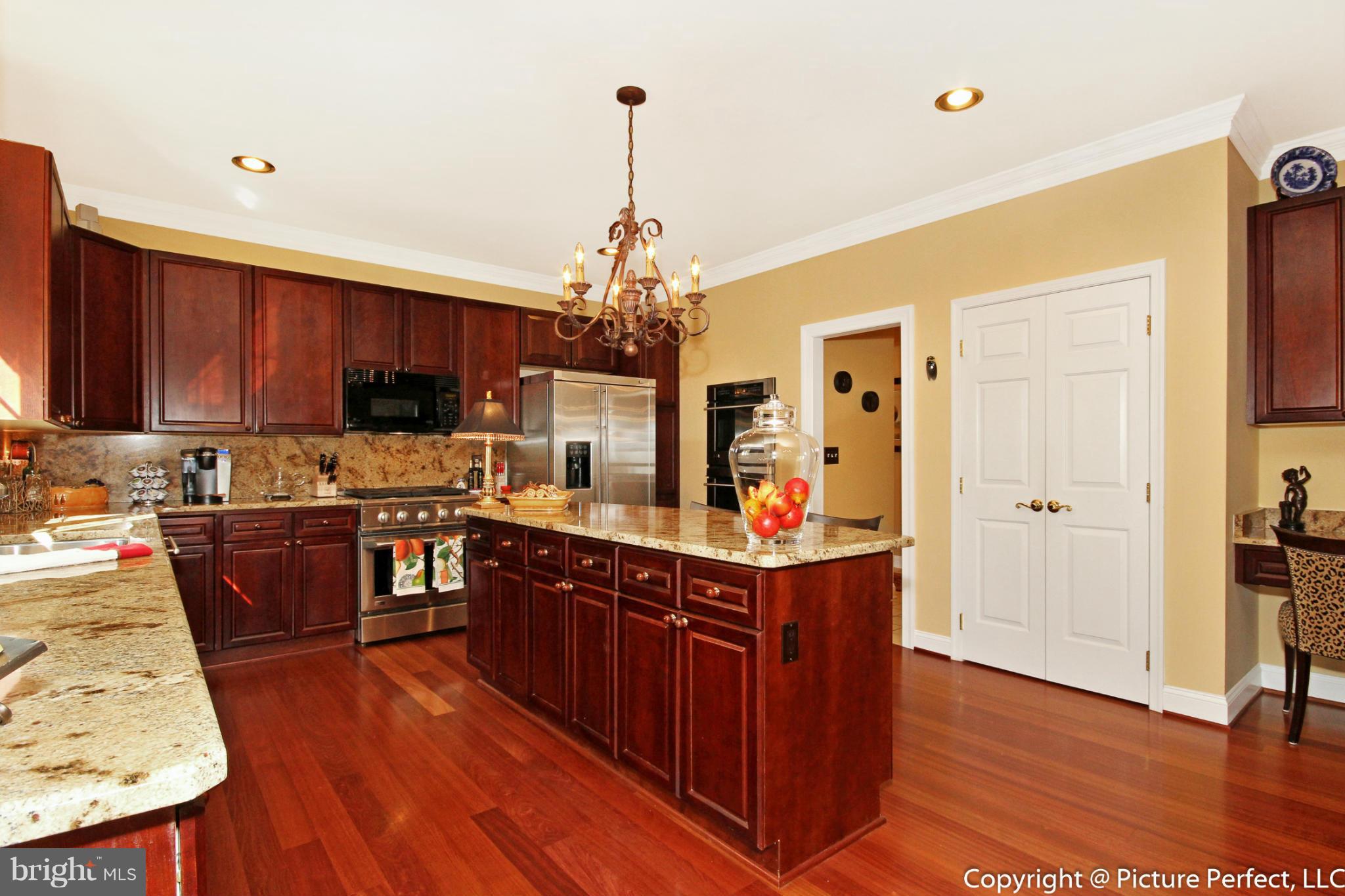 5380 Stone Road Frederick, MD 21703 - Photo 14 of 30 a kitchen with stainless steel appliances granite countertop wooden floors wooden cabinets a sink and a stove