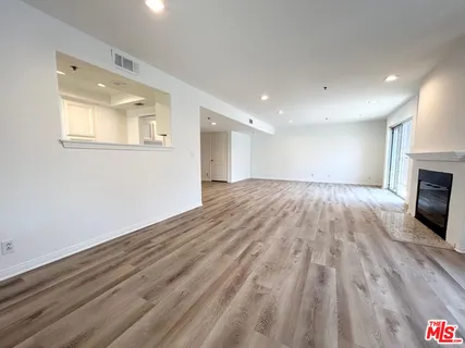 a view of empty room with wooden floor and fireplace