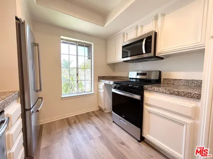 a kitchen with stainless steel appliances granite countertop a stove a microwave and white cabinets