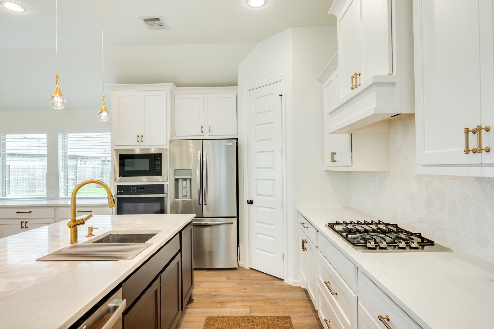 10115 Stride Court Rosharon, TX 77583 - Photo 10 of 40 Stunning chef's kitchen featuring elegant quartz countertops, sophisticated gold-trim hardware, and a custom backsplash that adds a touch of modern luxury.