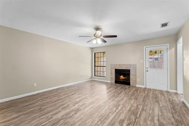 an empty room with windows fireplace and a wooden floor