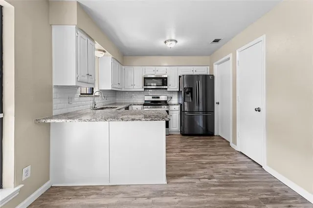 a kitchen with granite countertop a refrigerator and a stove top oven